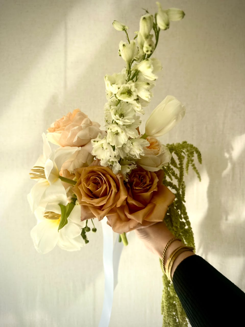 Abundant pedestal arrangement of copper roses, mauve roses, white cymbidium orchid and trailing green amaranthus